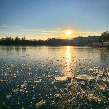 Sakin bir günbatımı, buz parçalarıyla dağılmış donmuş bir göle güzel bir yansıma bırakır.