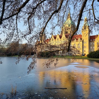 Günbatımında sakin ve sakin sulara yansıyan tarihi bir binanın nefes kesici ve çarpıcı manzarası Hannover Maschsee