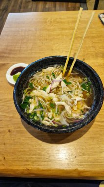 Canlı ve çekici bir kase sıcak erişte çorbası, taze sebzeler ve bol bol süslenmiş otlar.