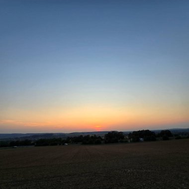 Nefes kesen güzel bir günbatımı, Deister Bad Nenndorf 'un huzurlu manzaralarını sıcacık renklerle kaplıyor.