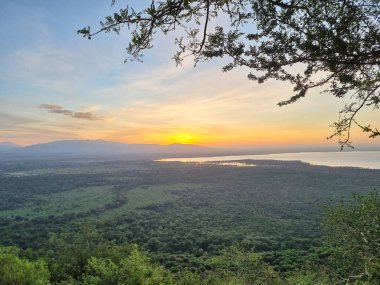 Canlı bir günbatımının nefes kesici görüntüsü huzurlu ve huzurlu bir göl olan Manyara Tanzanya Afrika 'yı çevreleyen yemyeşil yeşilliği gözler önüne seriyor.