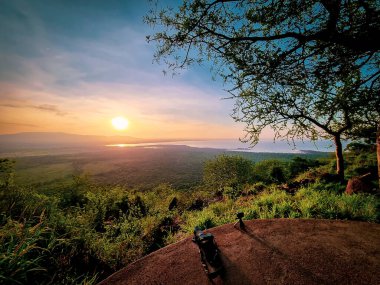 Parlak yeşil tepeleri ve sakin suları aydınlatan büyüleyici bir günbatımı, doğa meraklıları Manyara Tanzanya Gölü Afrika için ideal.