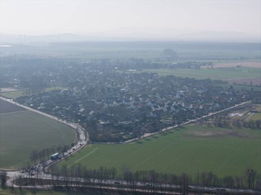 Nefes kesen hava manzarasında Wunstorf Kolenfeld 'in geniş, yemyeşil tarlaları arasında harmonik olarak yerleşmiş sakin bir köy görülüyor.