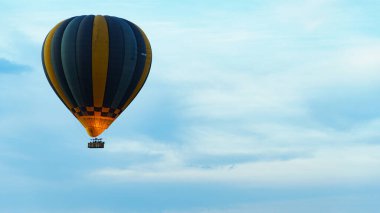 Canlı ve renkli bir sıcak hava balonu bulutlarla dolu huzurlu ve berrak bir mavi gökyüzüne doğru süzülür Serengeti Tanzanya Afrika