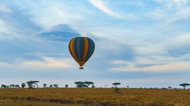 Canlı ve renkli bir sıcak hava balonu engin, güzel bir gökyüzü altında zarif bir şekilde süzülüyor Serengeti Tanzanya Afrika