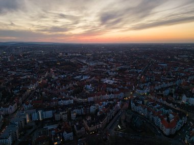 Nefes kesici bir hava görüntüsü alacakaranlıkta canlı bir şehir manzarası yakalıyor, gökyüzünde renkli bulutlar sergiliyor Hannover Listesinde Aşağı Saksonya