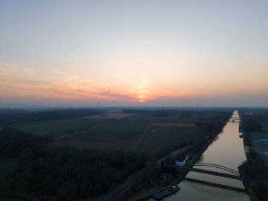 Huzurlu bir gün batımı huzurlu bir nehri yansıtıyor. Bereketli ve canlı manzaralarla çevrili. Hannover Seelze.