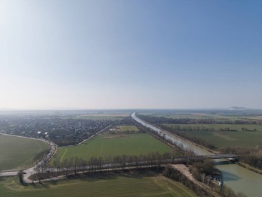 Bu hava manzarası canlı tarlaların yanında dolambaçlı bir su yolunun sükunetini yakalıyor, görkemli doğaları sergiliyor Wunstorf Kolenfeld Mittellandkanal