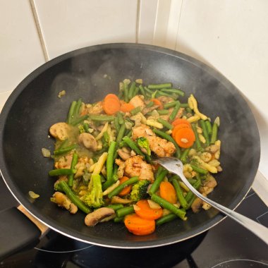 Lezzetli ve canlı sebzeler sıcak tavada ustalıkla kızartılır. Tazelik ve aşçılık becerileri sergiler.