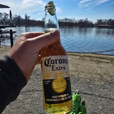 Sıcak ve güneşli bir günde arkadaşlar Maschsee Hannover 'la göl kenarındaki Corona Extra birasının tadını çıkarın.