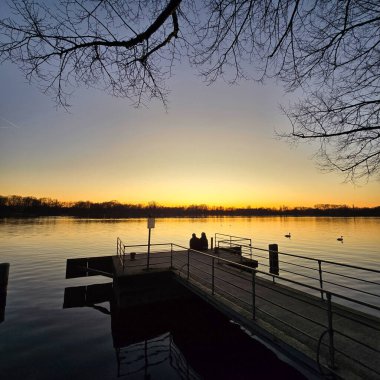 Suyun üzerinde sakin bir günbatımı sahnesi, muhteşem bir altın ufuk Maschsee Hannover karşısında güzel siluetler sergiliyor.