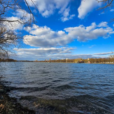 Huzurlu bir göl manzarası. Kıyıda hafif dalgalar ve bulutlarla dolu çarpıcı bir gökyüzü. Maschsee Hannover.