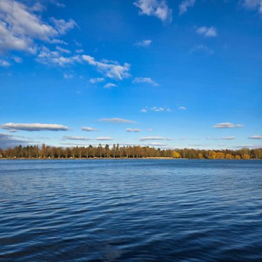 Bu huzurlu ve huzurlu göl manzarası sakin sular, canlı ağaçlar ve çarpıcı bir berrak gökyüzü olan Maschsee Hannover 'ı sergiliyor.