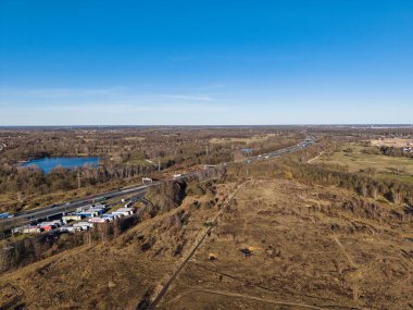 Açık arazileri ve mavi gökyüzüne karşı dolambaçlı bir yolu gösteren çarpıcı bir hava görüntüsü. Hannover Langenhagen Silbersee