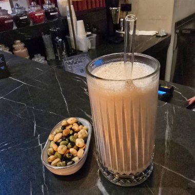 Lezzetli atıştırmalıkların yanında köpüklü bir protein içeceği, hepsi zarif ve şık bir bar ortamında servis edilir.