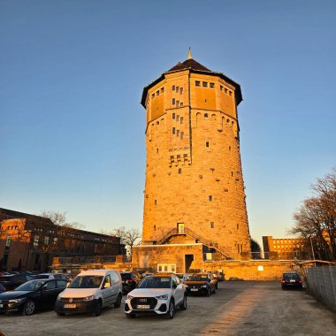 Tarihi bir yapı, Hannover Wasserturm mimari zarafetini sergileyen günbatımının çarpıcı renkleriyle aydınlanır.
