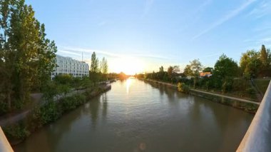Gün batımında nehrin görkemli ve hareketli manzarası, yemyeşil ve sakin sularla güzelce çerçevelenmiş Hannover Mittellandkanal