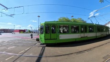 Verimli toplu taşımacılık Hannover Vahrenwald 'ın zarafetini vurgulayarak güneşli bir şehir manzarasında yeşil tramvaylar süzülüyor.