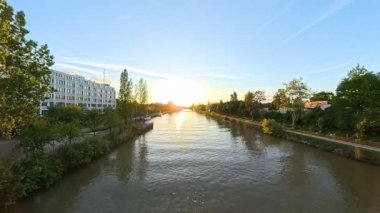 Şaşırtıcı derecede güzel bir hipersüratli gün batımı, Hannover Mittellandkanal yakınlarındaki pitoresk nehri yansıtarak sakin suları aydınlatıyor.