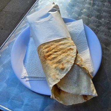 Lezzetli bir Shawarma tortilla dürümü tabakta güzelce sunuluyor. Yanında da iştah açıcı bir sunum için güzelce katlanmış bir peçete.