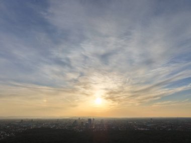 Engin, geniş bir şehrin üzerinde nefes kesici bir günbatımı manzarası sergileniyor. Canlı bulutlar ve ılık altın sarısı Hannover Listesi.