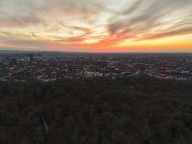 Nefes kesici bir hava manzarası canlı bir günbatımını gösteriyor. Şehrin ufuk çizgisini ve doğayı aydınlatıyor. Hannover Aşağı Saksonya