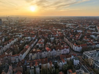 Havadan bakıldığında şehrin üzerinde çarpıcı bir günbatımı, canlı çatılar ve ışıldayan ufuk çizgisi Aşağı Saksonya