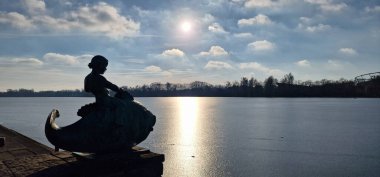 Güzel, dingin bir deniz kızı heykeli zarif bir şekilde suyla kaplı, güneş ışığıyla yıkanmış, Maschsee Hannover.