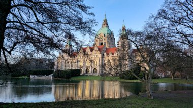 Büyüleyici güzellikte tarihi bir binanın manzarası sakin bir göle yansıyor, yemyeşil ağaçlarla çevrili Maschsee Hannover.