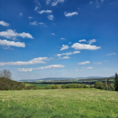 Bereketli yeşil tarlalar ve dağınık bulutlarla dolu açık mavi bir gökyüzü içeren inanılmaz güzel bir kırsal manzara.