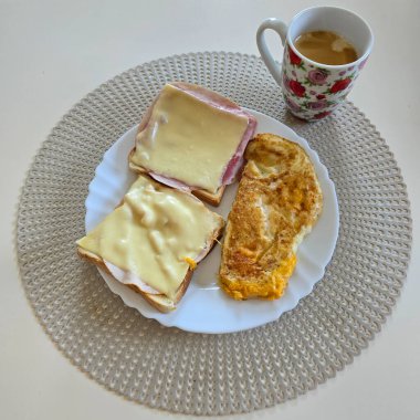 Tost, lezzetli peynir, lezzetli jambon ve şık bir tabakta yumuşak bir omlet ile doyurucu bir kahvaltı.