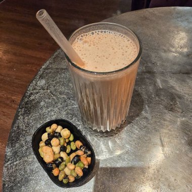 Tazeleyici ve soğuk bir içecek, dokulu bir masanın üstünde renkli bir çeşit atıştırmalıkla birlikte güzel bir şekilde servis edilir.