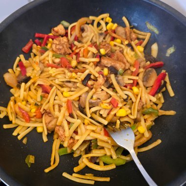 Taze erişte, taze tavuk ve renkli sebzelerden oluşan canlı ve lezzetli bir kızartma tabağı.