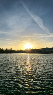 Nefes kesici ve huzurlu bir gün batımı, ılık bir parıltı yayıyor. Gökyüzünü huzur dolu bir su yüzeyinin üzerinde aydınlatıyor. Maschsee Hannover.