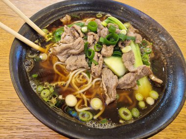 Lezzetli ve lezzetli bir kase lezzetli erişte çorbası üzerine taze et dilimleri ve taze taze soğan.