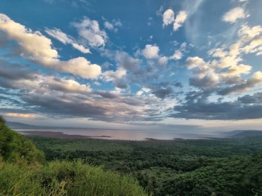Yamaçtan nefes kesici bir manzara canlı yeşillik ve çarpıcı bulutlarla dolu bir gökyüzü sergiliyor.