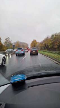 Yağmurlu bir trafik sıkışıklığı, kaygan, ıslak yollardaki çeşitli araçlar Bielefeld üzerindeki bulutlu gökyüzünü güzel bir şekilde yansıtıyor.