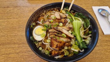 Üzerine mükemmel ızgara tavuk, yumuşak yumurta ve taze sebzeler konmuş lezzetli bir kase ramen.