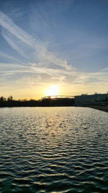 Şok edici bir günbatımı, huzurlu bir su kütlesinin üzerine altın renkler döküyor, doğal güzelliğini önemli ölçüde artırıyor.