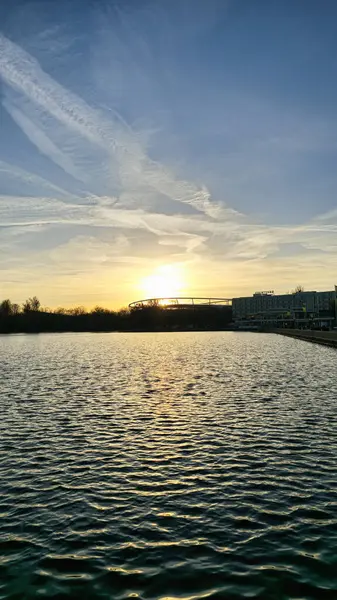 Şok edici bir günbatımı, huzurlu bir su kütlesinin üzerine altın renkler döküyor, doğal güzelliğini önemli ölçüde artırıyor.