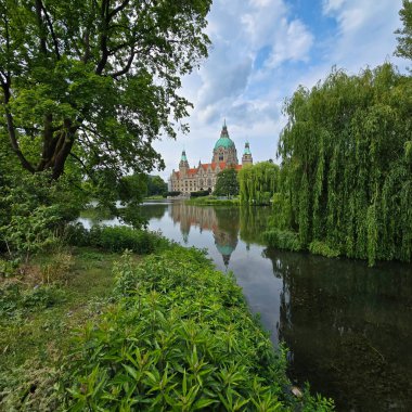 Yeşillik yeşili Maschpark Hannover ile çevrili sakin bir göle yansıyan görkemli bir şatonun şaşırtıcı derecede güzel bir manzarası.