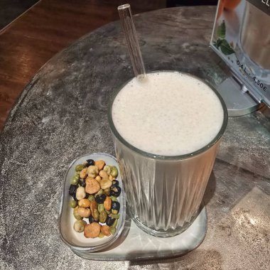 Lezzetli ve ferahlatıcı bir meyve püresi, şık bir kafe masasına kurulmuş lezzetli fındık çeşitleriyle eşleştirilmiş.