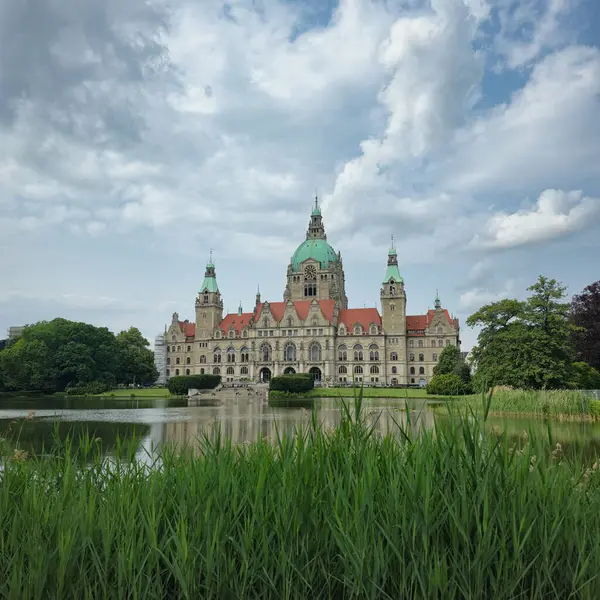 Yeşillik ve güzel su yansımalarının ön plandaki Maschpark Hannover 'da bulunduğu tarihi mimarinin çarpıcı bir örneği.