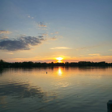 Göz kamaştırıcı günbatımı gökyüzünü aydınlatıyor ve huzur dolu Maschsee Hannover gölünün sakin yüzeyine güzel bir şekilde yansıtıyor.