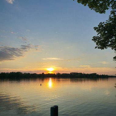 Sakin bir günbatımı, yemyeşil yemyeşil bir çerçeve ile çerçevelenmiş sakin su yansıtır nefes kesici, resimli bir sahne Maschsee Hannover