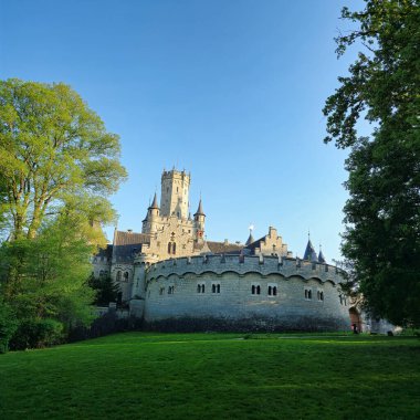 Fevkalade bir kalenin nefes kesici manzarası canlı yeşil ağaçlar ve açık mavi gökyüzü Schloss Marienburg Hannover Pattensen 'e karşı kurulmuş.