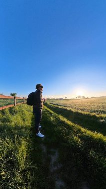 Gün doğarken Wunstorf Kolenfeld 'in canlı bir tarlasında kendini neşeyle suya daldıran bir adamı resmeden sakin bir sahne. 