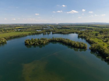 Güzel bir günde, Koldinger Pattensen 'in Hannover Pattensen' i izlediği güzel bir günde, berrak bir göl ve parlak, mavi bir gökyüzü altında bir hava görüntüsü yakalar.