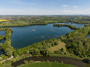 Bereketli yeşillikler ve sakin sular arasında yuva yapmış sakin bir gölü gösteren nefes kesici bir hava manzarasının tadını çıkarın Koldinger Hannover Pattensen 'i