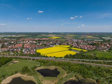 Göz kamaştırıcı hava manzarası açık mavi gökyüzü altında sarı alanlar, yeşillikler ve banliyö manzarası. Koldinger Hannover Pattensen 'i gördü